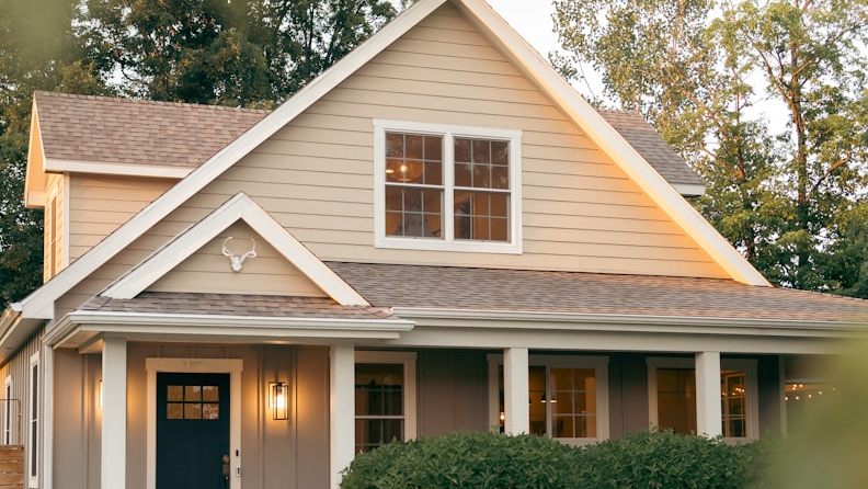 A repainted country home with a cream gable, gray siding and a navy front door